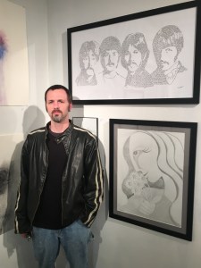Dennis Wells stands before some of his larger works on display at Delurk Gallery (Photo: Pat Berryhill)